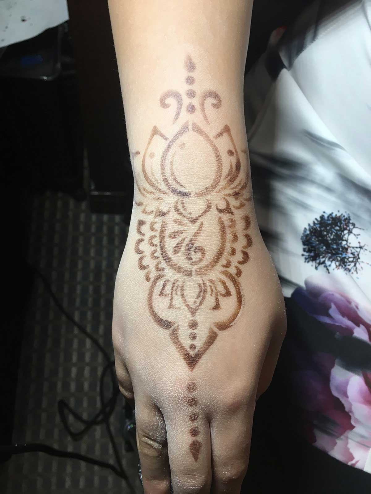 Intricate henna design on a person's hand and forearm.