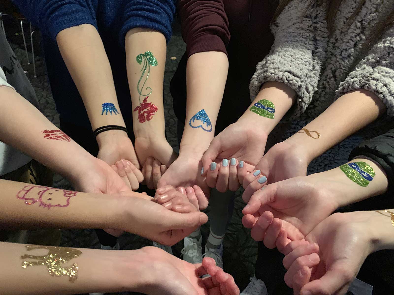 Group of teens showing off their various temporary tattoos received as bat mitzvah activities