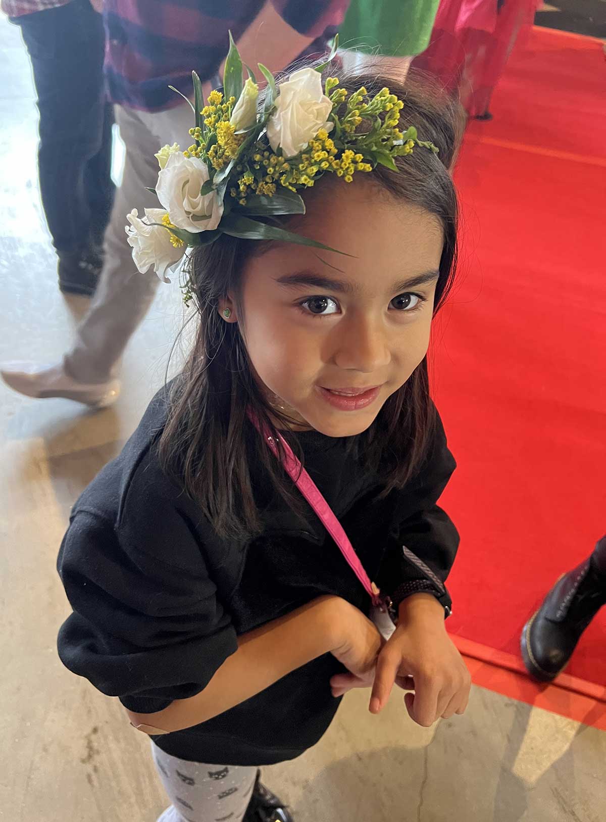 Young girl with a floral headband smiling at the camera.