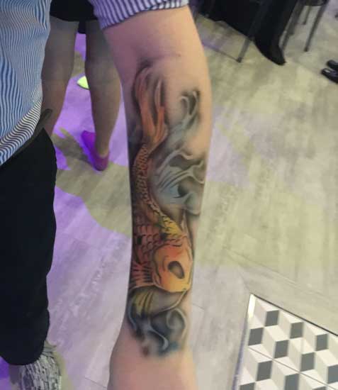 A person displaying a detailed koi fish tattoo on their arm.