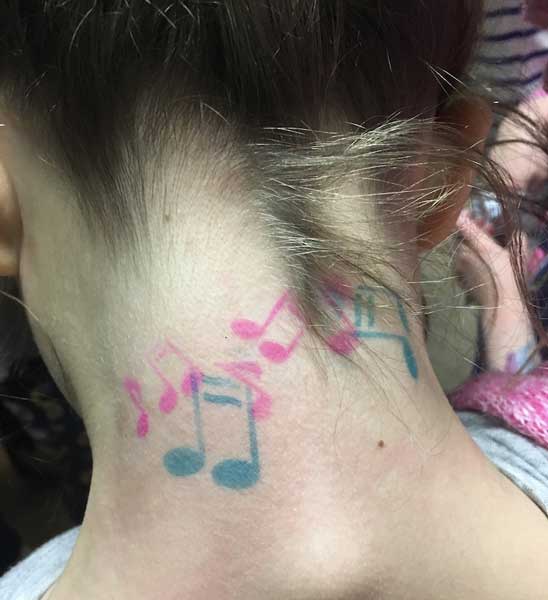 Music note tattoos on the back of a person's neck.