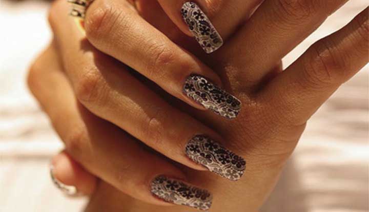 A close-up of hands with long, intricately patterned nail art.