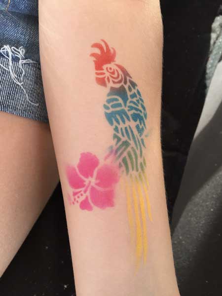 Temporary tattoo of a colorful rooster and pink flowers on a person's forearm.
