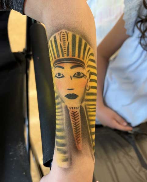 An egyptian pharaoh-inspired tattoo depicted on a person's forearm.
