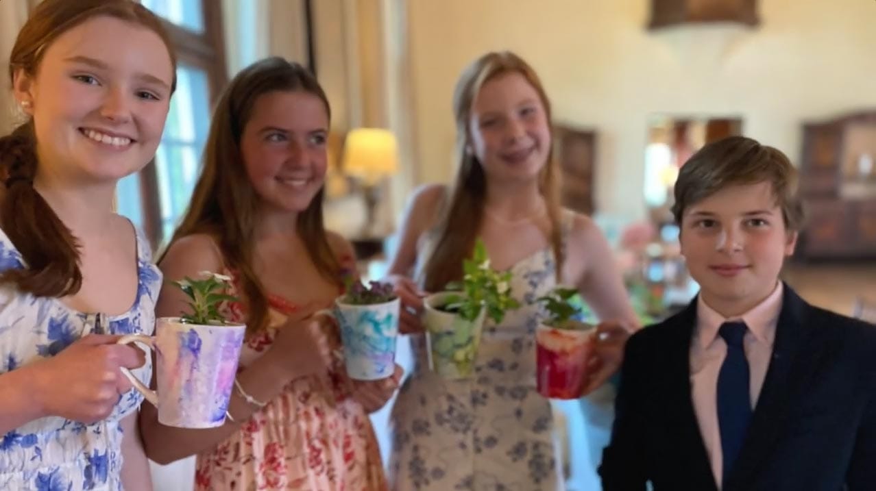 Four young people smiling and holding decorative cups with plants inside. These were bat mitzvah party favors.