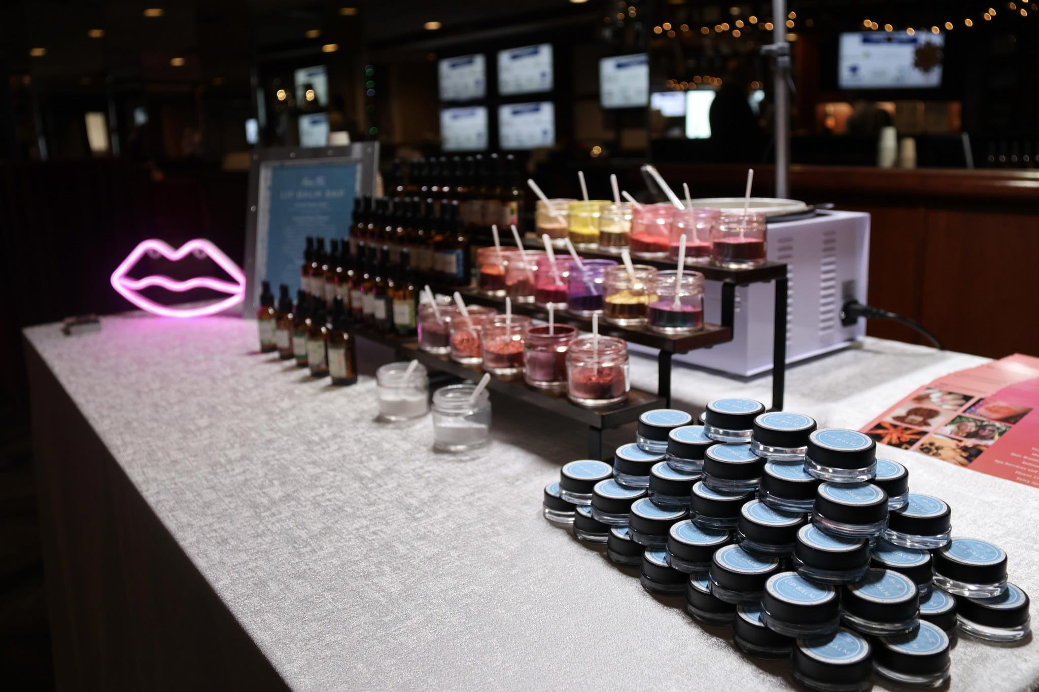 A cosmetics display at an event featuring a variety of lipsticks and other makeup products.