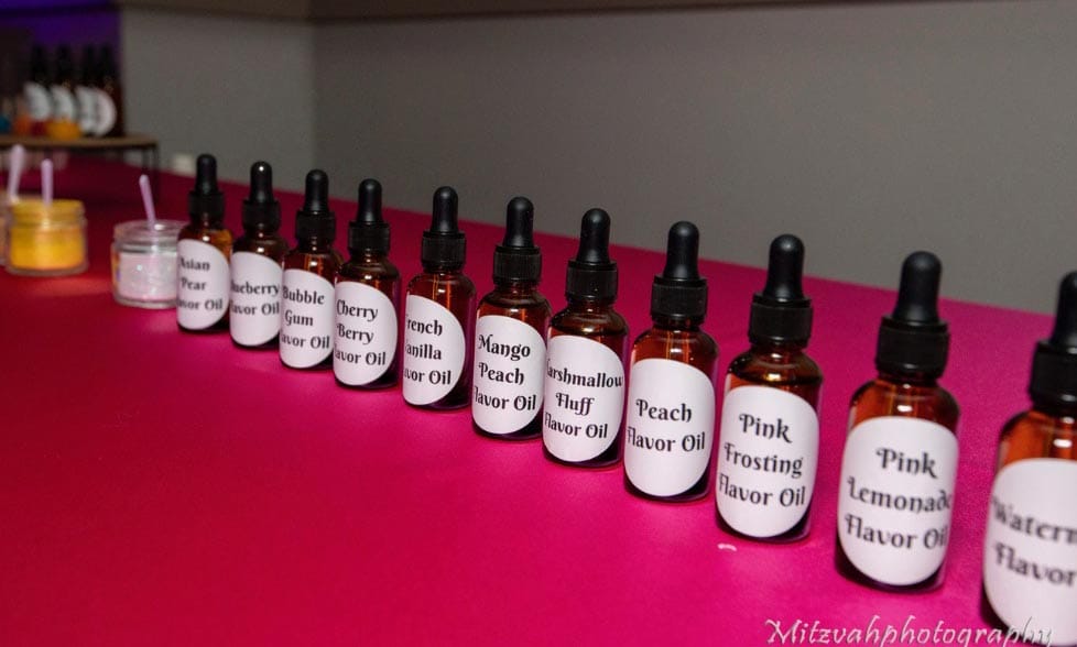 A collection of flavored oil bottles aligned on a pink surface.
