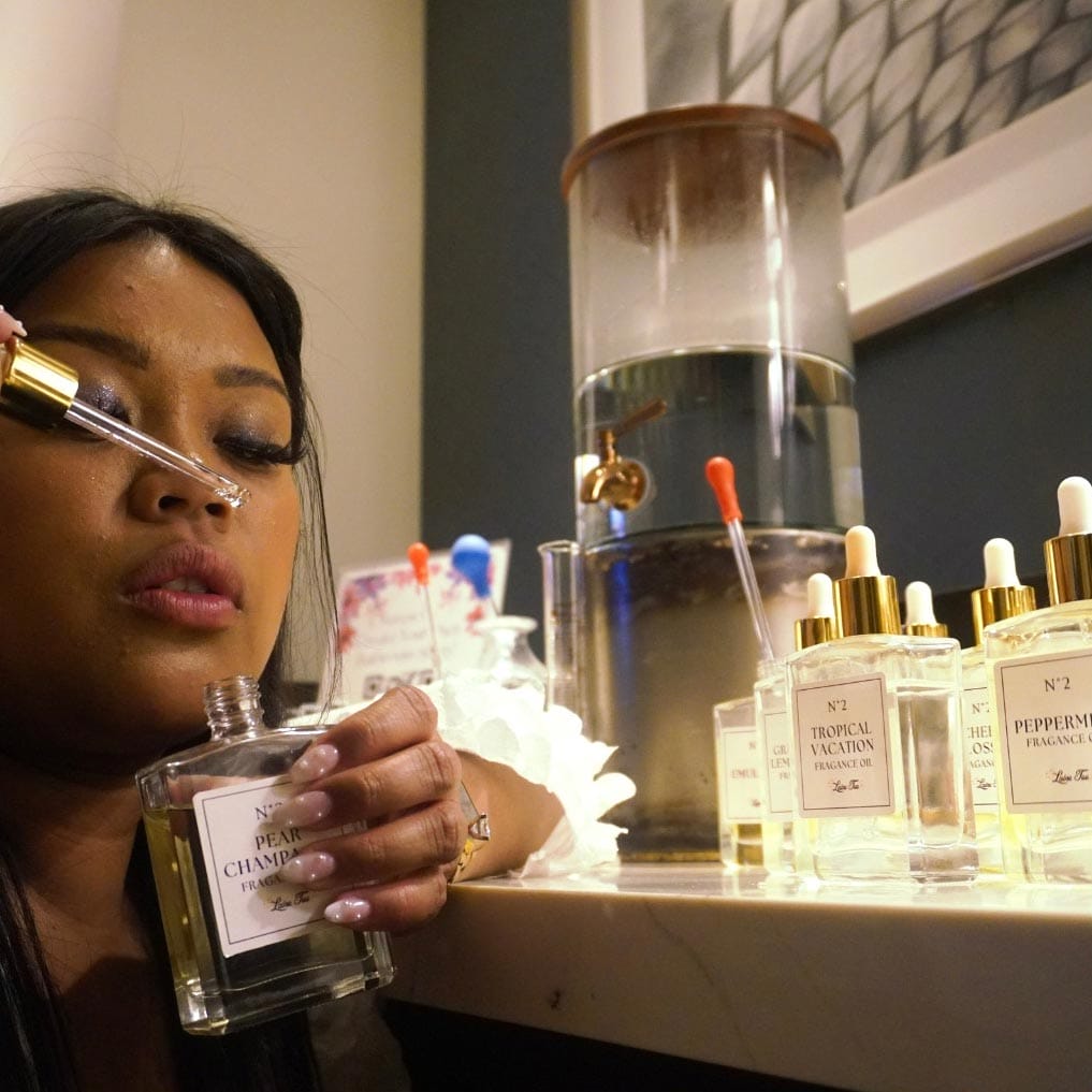 A person testing different perfume scents from small bottles at a fragrance counter.