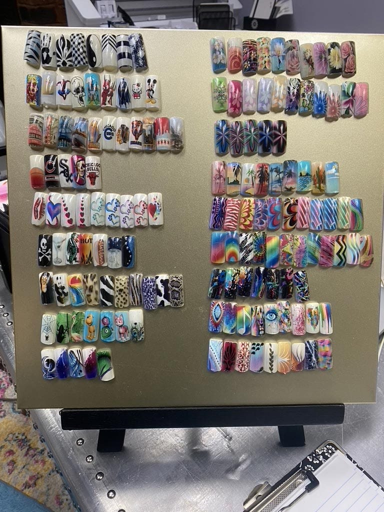 Display board showcasing a variety of colorful and patterned nail art designs.