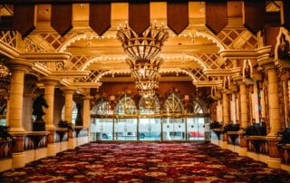 A sparking ballroom with chandeliers and plush carpet sits empty, before a gala.