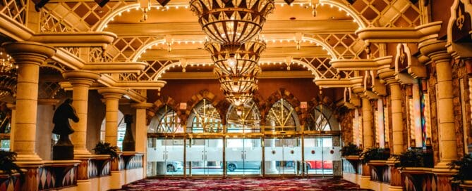 A sparking ballroom with chandeliers and plush carpet sits empty, before a gala.